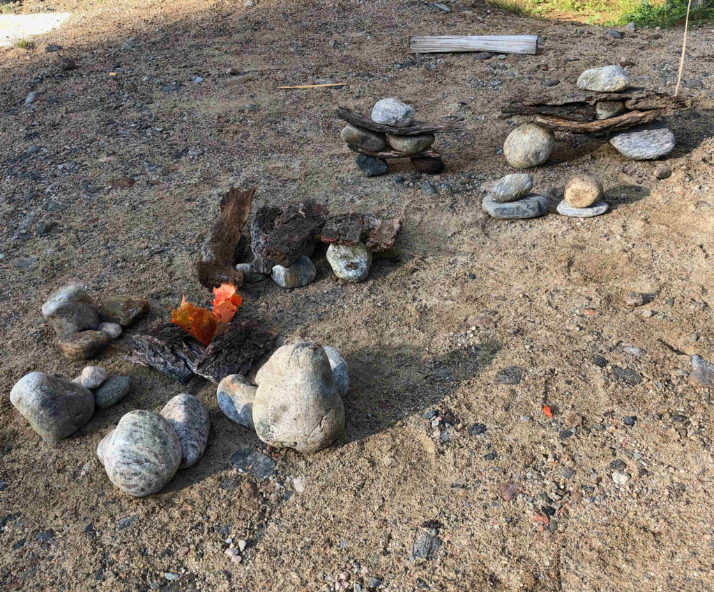 An artistic representation of our family sitting next to a campfire crafted out of rocks and bark.